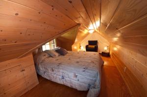 1 dormitorio en una cabaña de madera con 1 cama. en Chalet Paradis de Charlevoix, en Baie-Saint-Paul