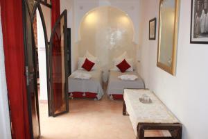 a room with two beds and a table in it at Riad Jnan El Cadi in Marrakesh