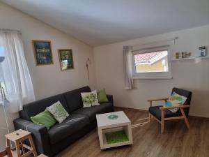 a living room with a black couch and a table at Das Taubenhaus in Hollersbach im Pinzgau