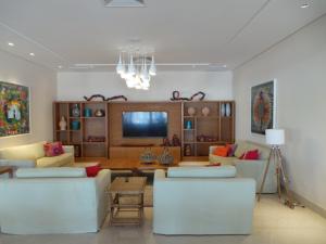 a living room with white couches and a television at Jatiuca Hotel & Resort in Maceió