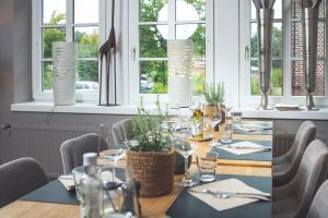 a dining room with a table and chairs and windows at Landart Hotel in Sittensen