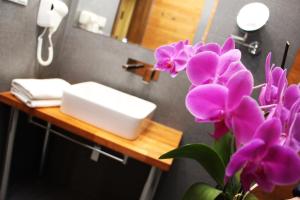łazienka z umywalką i fioletowymi kwiatami na ladzie w obiekcie Zajazd w Białej w mieście Grodzisk Wielkopolski