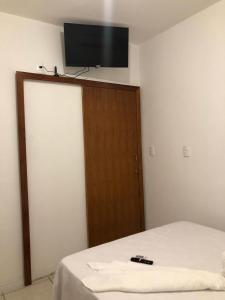 a bedroom with a bed and a television on the wall at Apto em Laguna a 10 min praia do Mar Grosso - 106 in Laguna