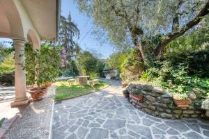 ogród z kamiennym chodnikiem i kamienną ścianą w obiekcie ApartmentsGarda - Residenza Bouganville w mieście Garda