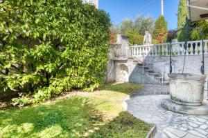eine Steintreppe mit einer Statue neben einem Busch in der Unterkunft ApartmentsGarda - Residenza Bouganville in Garda