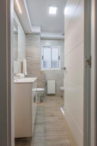 une salle de bain blanche avec un lavabo et des toilettes dans l'établissement Apartamentos Alameda del Tajo I Parquing Centro, à Ronda 67 autres photos