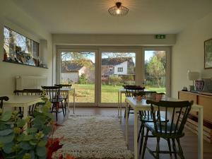 a living room with tables and chairs and a large window at B&B Les Lits de Nohaipré in Rendeux