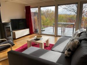 ein Wohnzimmer mit einem Sofa, einem TV und einem Tisch in der Unterkunft Terrasses de Malmedy Chalet l'undeuxtrois in Malmedy