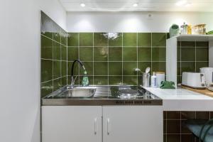 uma cozinha com um lavatório e uma parede de azulejos verdes em Origo Vendégház em Hévíz