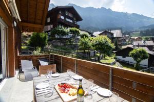 a table on a balcony with a bottle of wine at Chalet Hannegg Penthouse in Wengen