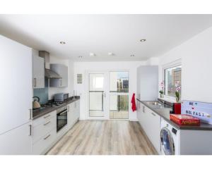 una cucina con armadietti bianchi e pavimenti in legno di Central Belfast Apartments Sandford a Belfast