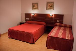 Dos camas en una habitación de hotel con sábanas rojas. en Norte Hotel, en Villanueva de Gállego