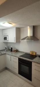 a kitchen with white cabinets and a black stove top oven at Villa in Parque Santiago 1 , sea View and all the Confort That you Need! in Playa de las Americas