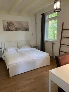 een slaapkamer met een wit bed en een raam bij Tofino, een comfortabel vakantiehuis naast een bos en zwemmeer in Gasselte