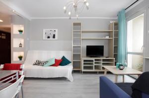 uma sala de estar com uma cama branca e uma televisão em Apartament Słoneczny em Gdynia