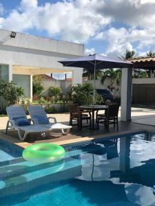 una mesa con sillas y una sombrilla junto a la piscina en Terra Bahia, en Aracaju