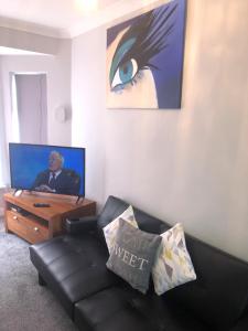 a living room with a couch and a tv at Graceful Home Away Sittingbourne in Sittingbourne