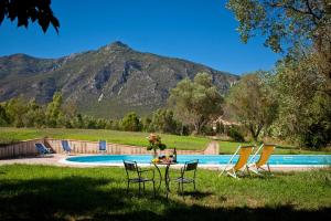 einen Tisch und Stühle im Gras in der Nähe eines Pools in der Unterkunft Casa vacanze Maria Maddalena 1 Iglesias in Iglesias