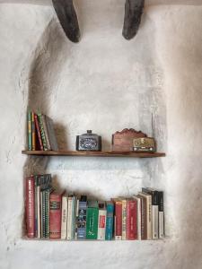 un estante con libros y un reloj en él en Casa Juncaria, en Yunquera