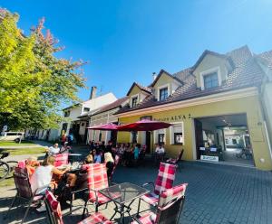 een groep mensen die aan een tafel voor een gebouw zitten bij Alva Pension 2 in Mikulov