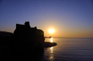 a sunset over the ocean with the sun setting at Oasis in Acitrezza