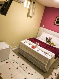ein Schlafzimmer mit einem Bett mit roten Blumen auf dem Boden in der Unterkunft Pousada Caminho dos Anjos in Arraial do Cabo