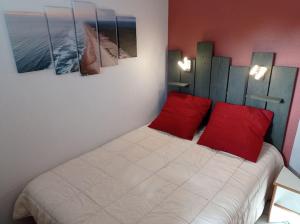 1 dormitorio con 1 cama con 2 almohadas rojas en Vue Golf dans Résidence Nature "SYMPALAPPART", en Moliets-et-Maa