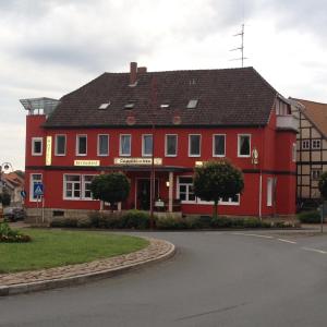 a red building with a black roof on a street at Hotel Cappuccino in Elze