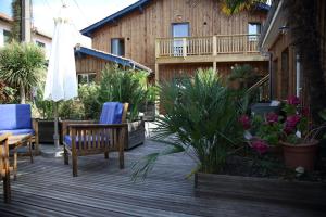 a deck with chairs and an umbrella and some plants at Hotel du Cap in Cap-Ferret