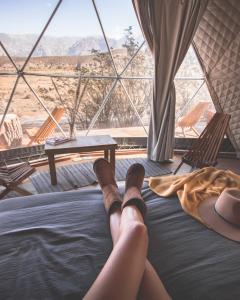 a person laying on a bed in a room with a view at Domos Uspallata in Uspallata