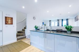 una cocina con armarios blancos y una escalera en PIPI HOMES en Mánchester