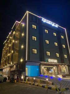 a hotel building with a sign on it at night at السامية الفندقية in Sharurah