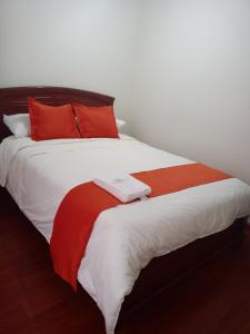 a bedroom with a large bed with red and white sheets at Hotel Sello Dorado in Pasto