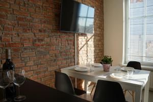een eetkamer met een witte tafel en een bakstenen muur bij Apartament Gliwice Centrum Witkiewicza II in Gliwice