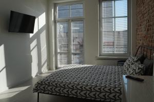 een slaapkamer met een bed in een kamer met ramen bij Apartament Gliwice Centrum Witkiewicza II in Gliwice