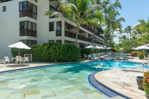 einen Pool vor einem Hotel mit Palmen in der Unterkunft Nannai Residence Frente Piscina Muro Alto Beira Mar in Porto De Galinhas