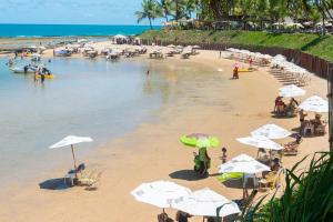 ein Strand mit weißen Sonnenschirmen und Menschen am Strand in der Unterkunft Nannai Residence Frente Piscina Muro Alto Beira Mar in Porto De Galinhas