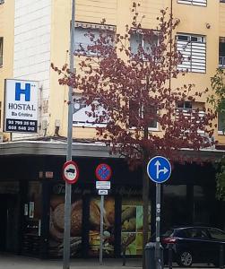 un árbol frente a un edificio con letreros en la calle en Hostal Isla Cristina Mataro, en Mataró