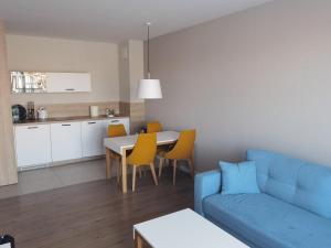 a living room with a blue couch and a kitchen at Meduza w Bel Mare in Międzyzdroje