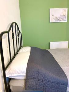 een bed in een kamer met groene muren bij Fidelissima Apartman in Sopron