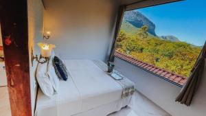 a bed in a room with a view of a train window at Pousada Rosa dos Ventos Capão in Vale do Capao