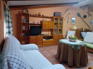 uma sala de estar com sofás, uma mesa e uma televisão em Alojamiento Rural Puente Honda em Siles