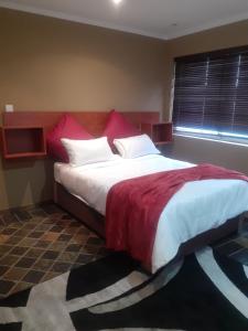 a bedroom with a large bed with red and white pillows at Sasha guest house in Johannesburg