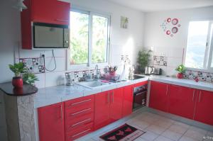 a kitchen with red cabinets and a sink at Résid’calonne in Le François