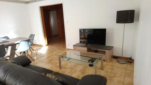 sala de estar con sofá, mesa y TV en Apart'Bellevue, en Morez