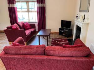a living room with a red couch and a fireplace at Burnmon Cottage in Belcoo