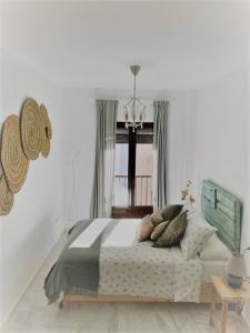 a bedroom with a bed with pillows and a chandelier at El Envero Apartamento in Jerez de la Frontera +48 photos