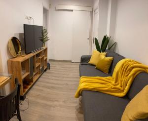 a living room with a blue couch with a yellow blanket at Nuestro Rinconcito del Soho in Málaga