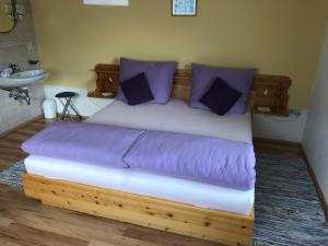 a wooden bed with purple pillows in a bedroom at Ferienwohnung Radler in Stumm