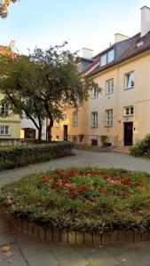 a garden with red flowers in front of a building at Rycerska - Stone Steps Apartments in Warsaw